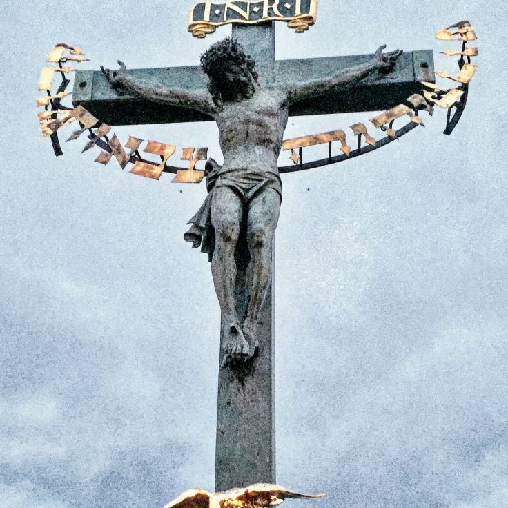 The Crucifix and Calvary (Prague). There are 30 statues mounted to the balustrade of Charles Bridge in Prague. This sculpture is one of the most historically interesting sculptures on the bridge, which gradually gained its present appearance throughout many centuries. The original wooden crucifix was installed at this place soon after 1361 and probably destroyed by the Hussites in 1419. A new crucifix with a wooden corpus was erected in 1629 but was severely damaged by the Swedes towards the end of the Thirty Years' War. The remnants of this crucifix can be found in the lapidarium of the National Museum in Prague. This was replaced by another wooden Calvary which, in turn, was replaced with a metal version in 1657. Bought in Dresden, this crucifix was originally made in 1629 by H. Hillger based upon a design by W. E. Brohn. In 1666, two lead figures were added, but these were replaced in 1861 by the present sandstone statues by Emanuel Max, portraying the Virgin Mary and John the Evangelist. The golden Hebrew text on the crucifix was added in 1696 and is a prime example of Medieval European anti-Semitism. In that year, the Prague authorities accused a local Jewish leader, one Elias Backoffen, of blasphemy. As his punishment he was ordered to raise the funds for purchasing of gold-plated Hebrew letters, placed around the head of the statue, spelling out "Holy, Holy, Holy, the Lord of Hosts," the Kedusha from the Hebrew prayer and originating in the vision from the Book of Isaiah. The inscription was a symbolic humiliation and degradation of Prague Jews, forcing them to pay for a set of golden letters referring to God and hung around the neck of the statue of Christ (information from Steven Plaut, The "Vav" from the Charles Bridge). A bronze tablet with explanatory text in Czech, English and Hebrew was mounted under the statue by the City of Prague in 2000. The tablet's placement came after an American Rabbi, Ronald Brown of Temple Beth Am in Merrick, New York was passing over the bridge and noted the possibly offensive nature of the placing of the text. Upon a direct request to the mayor, the tablet was soon placed to the side of the statue.